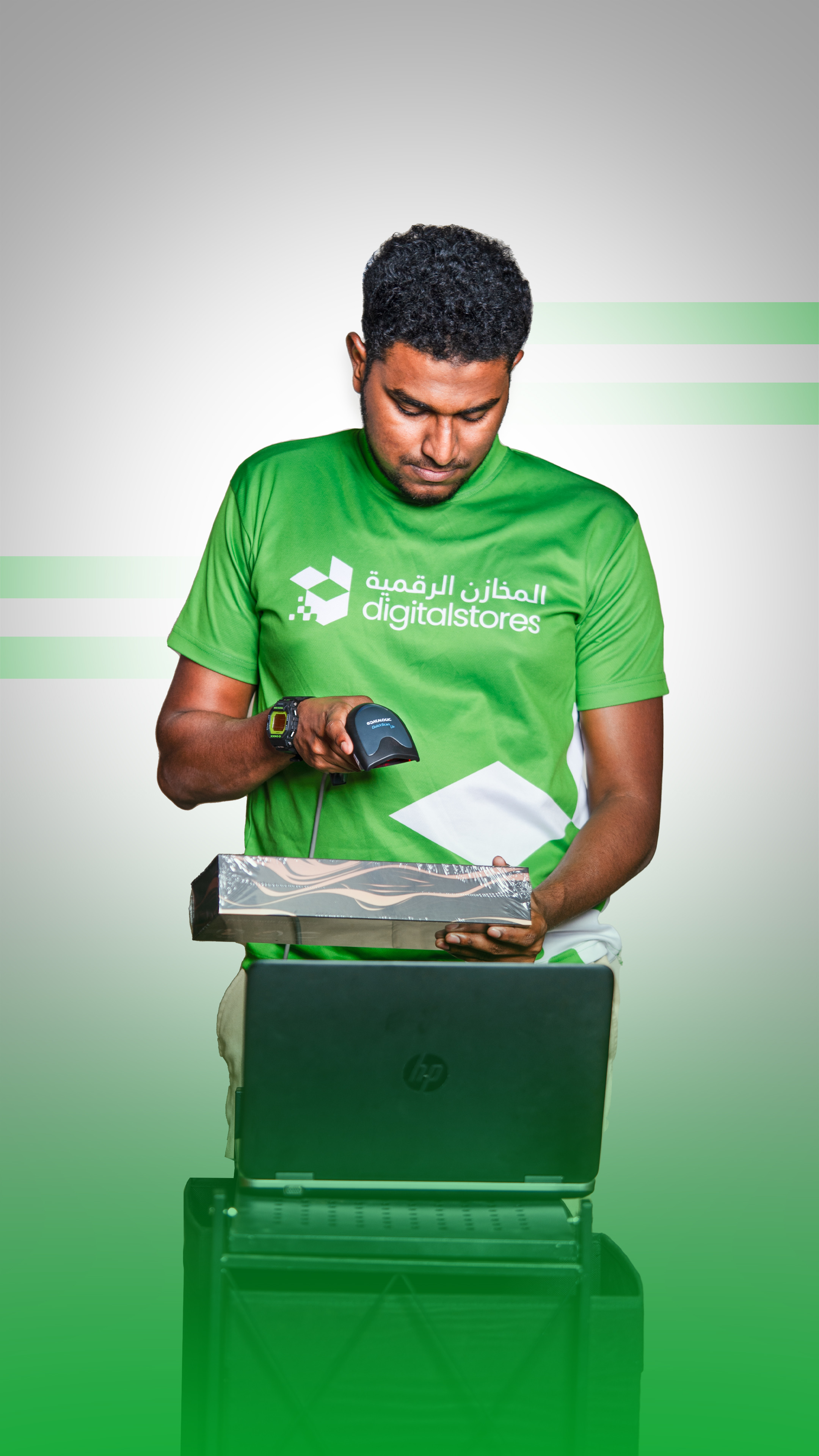 A DigitalStores associate in a branded green uniform scanning a package over a laptop at the fulfillment station